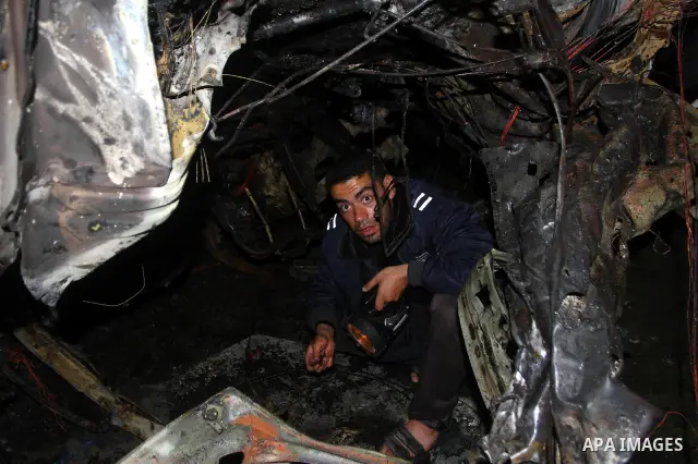 Palestinian Hamas officer inspects a vehicle following an Israeli airstrike that killed three of Hamas militants near Deir Al Balah, central Gaza Strip, early Saturday, April 2, 2011. Israeli aircraft killed the militant...