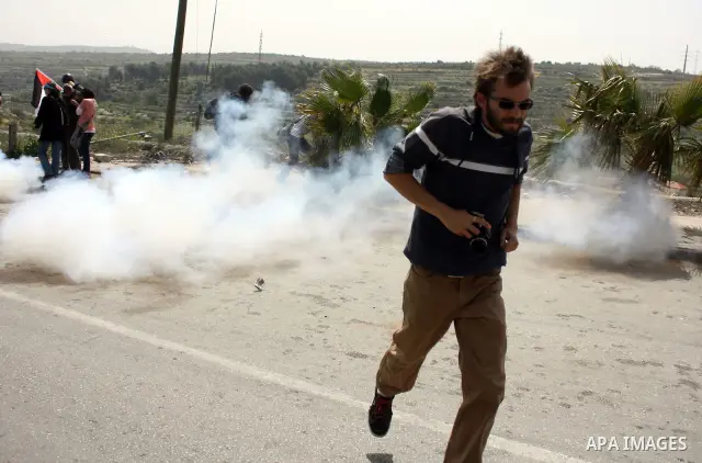 A demonstrator run for cover from tear gas fired by Israeli soldiers during a protest by foreign, Israeli and Palestinian demonstrators against the controversial Israeli separation barrier, in the Palestinian village of...