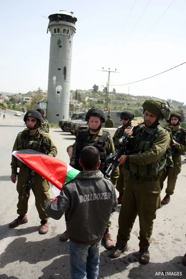 A Palestinian boy argues with Israeli soldiers during a protest by foreign, Israeli and Palestinian demonstrators against the controversial Israeli separation barrier, in the Palestinian village of Beit Omar, near the We...