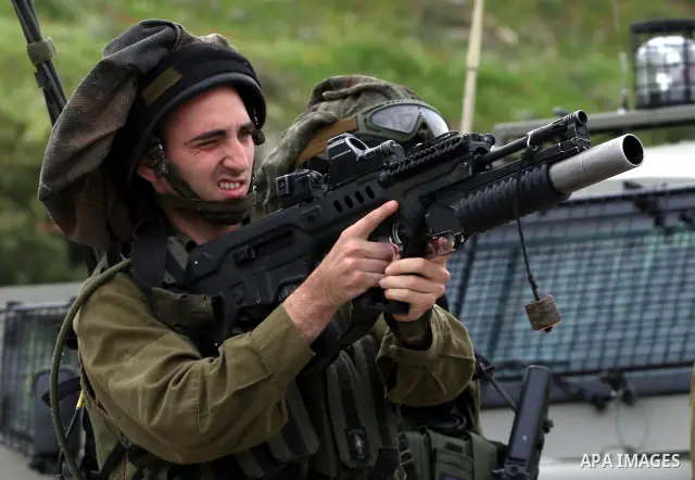 An Israeli soldier prepares to fire tear gas canister towards Palestinian youths during a demonstration against the expansion of the nearby Jewish settlement of Halamish in the West Bank village of Nabi Saleh near Ramall...