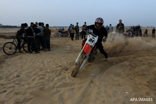 A Palestinian man rides his motorcycle on sand dunes during the weekly sport event in the Gaza Strip town of al-Zahra, south of Gaza City, on April 1,2011. Palestinian youths use the dunes for riding their motorcycles, h...