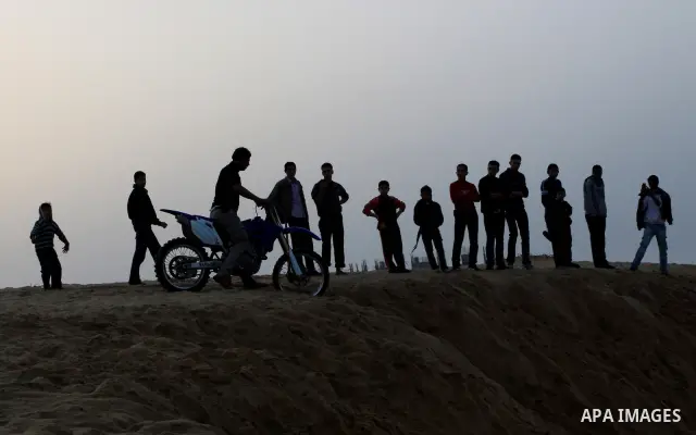 A Palestinian man rides his motorcycle on sand dunes during the weekly sport event in the Gaza Strip town of al-Zahra, south of Gaza City, on April 1,2011. Palestinian youths use the dunes for riding their motorcycles, h...