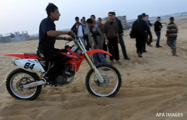 A Palestinian man rides his motorcycle on sand dunes during the weekly sport event in the Gaza Strip town of al-Zahra, south of Gaza City, on April 1,2011. Palestinian youths use the dunes for riding their motorcycles, h...