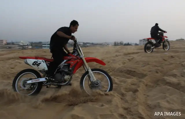 A Palestinian man rides his motorcycle on sand dunes during the weekly sport event in the Gaza Strip town of al-Zahra, south of Gaza City, on April 1,2011. Palestinian youths use the dunes for riding their motorcycles, h...