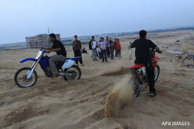 A Palestinian man rides his motorcycle on sand dunes during the weekly sport event in the Gaza Strip town of al-Zahra, south of Gaza City, on April 1,2011. Palestinian youths use the dunes for riding their motorcycles, h...