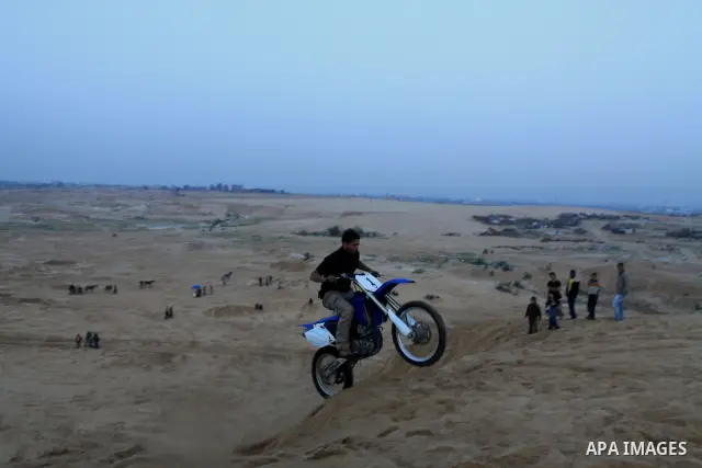 A Palestinian man rides his motorcycle on sand dunes during the weekly sport event in the Gaza Strip town of al-Zahra, south of Gaza City, on April 1,2011. Palestinian youths use the dunes for riding their motorcycles, h...