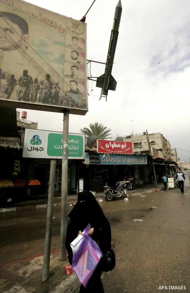 Palestinians walk past posters in Rafah in the southern Gaza Strip, on April 4, 2011, a day after Israel demanded that the United Nations bin a report critical of its deadly 2008-2009 offensive on Gaza after the author s...