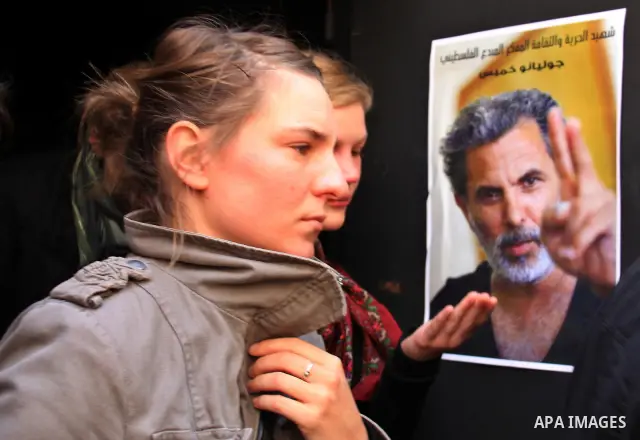 Women walk past a poster of Arab-Jewish actor and director Juliano Mer-Khamis outside The Freedom Theatre, owned by Mer Khamis, in Jenin refugee camp, near the West Bank city of Jenin April 5, 2011. A senior Palestinian...