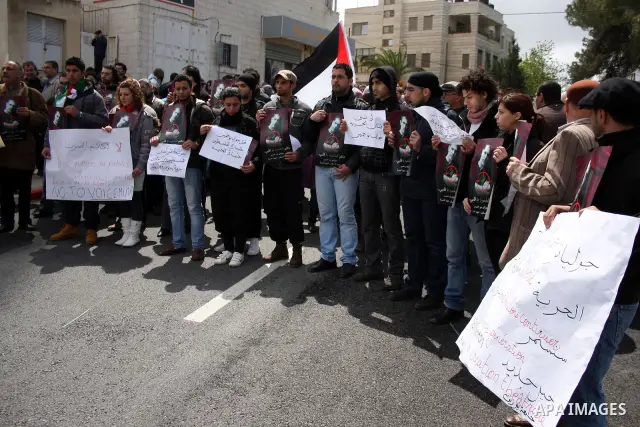 Palestinians hold signs and posters depicting Arab-Israeli actor and director Juliano Mer Khamis during a rally in the West Bank city of Ramallah on April 5, 2011. A senior Palestinian security official said on Tuesday p...