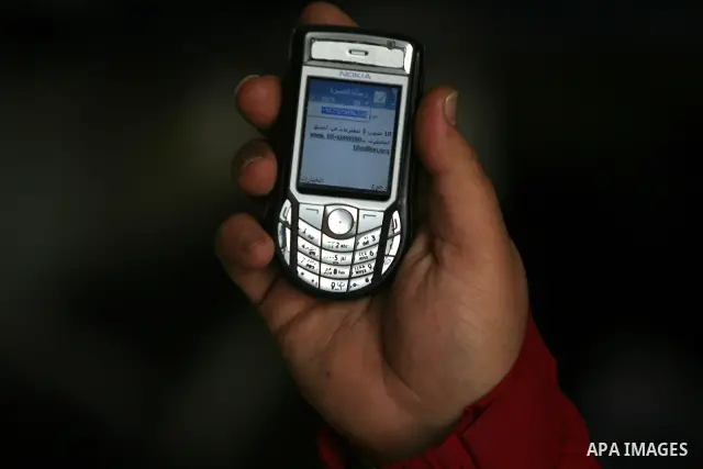 Palestinian man looks at his mobile phone after he received SMS message from the Israeli intelligence in Rafah, southern Gaza Strip on April 05,2011. Israeli intelligence services use SMS messages to search for the soldi...