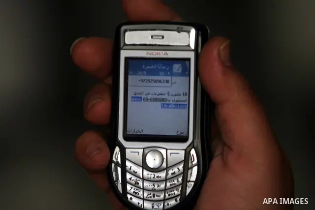 Palestinian man looks at his mobile phone after he received SMS message from the Israeli intelligence in Rafah, southern Gaza Strip on April 05,2011. Israeli intelligence services use SMS messages to search for the soldi...