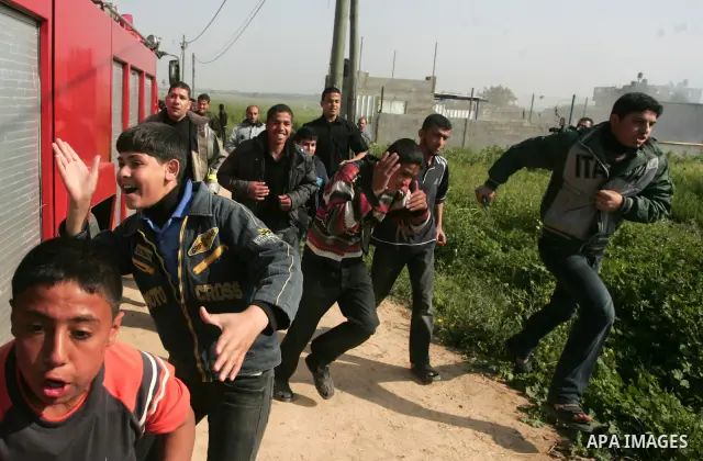 Palestinian youths run for cover from Israeli shell fired from a tank in east Gaza Strip on April 7, 2011 after Israeli troops shelled two separate areas in Gaza, killing one person and wounded at least 10. Photo by Moha...