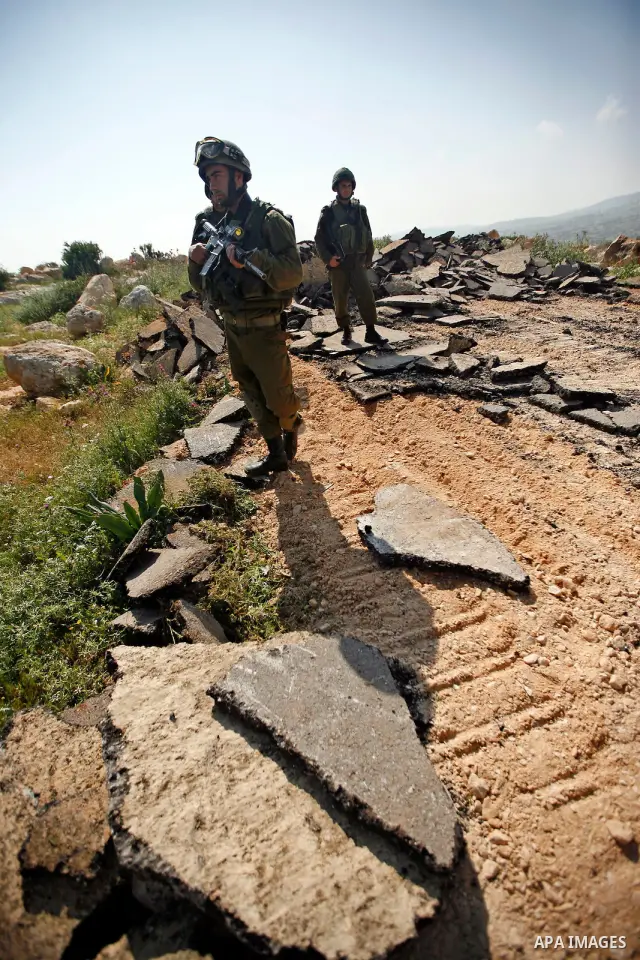 An Israeli earth-mover destroys a main road in Aqaba near the West Bank village of Tubas in the northern Jenin region on April 7, 2011 as the military used bulldozers to destroy Palestinian houses in another farming vill...
