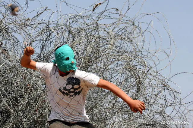 A Palestinian protestor hurls stones at Israeli soldiers during the weekly demonstration against Israel's separation barrier in the West Bank village of Nilin, near Ramallah, Friday, April 8, 2011. Israel says the barrie...