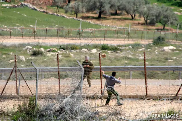 A Palestinian protestor hurls a stone towards an Israeli soldier during the weekly demonstration against Israel's separation barrier in the West Bank village of Bilin, near Ramallah, Friday, April 8, 2011. Israel says th...