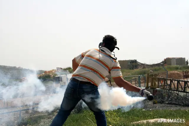 A Palestinian protestor returns tear gas canister fired by Israeli soldiers during the weekly demonstration against Israel's separation barrier in the West Bank village of Bilin, near Ramallah, Friday, April 8, 2011. Isr...