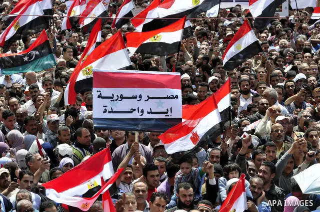 Egyptians hold flags and shout slogans as tens of thousands gathered for a demonstration at Cairo's Tahrir Square on April 8, 2011, two months after president Hosni Mubarak was ousted, to demand that former regime offici...