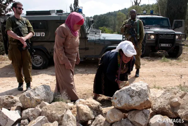 A Palestinian woman quarrels with Israeli soldiers during a protest rally against Jewish settlers in the West Bank village of Yatta, south of Hebron, on April 09,2011.Photo by Najeh Hahlamoun
