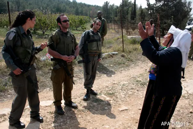 A Palestinian woman quarrels with Israeli soldiers during a protest rally against Jewish settlers in the West Bank village of Yatta, south of Hebron, on April 09,2011.Photo by Najeh Hahlamoun