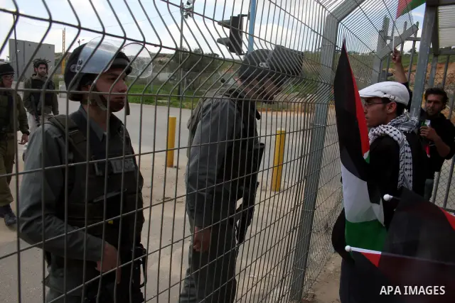 Palestinians stand at the gate of the Israeli controlled Ofer jail during a protest calling for the release of prisoners in the West Bank city of Ramallah on April 10,2011. Photo by Issam Rimawi