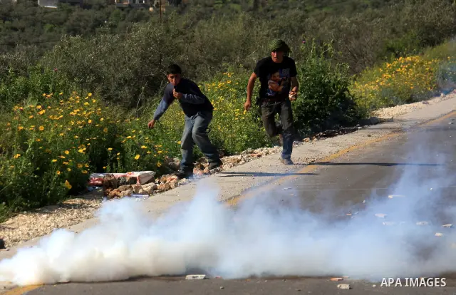 Palestinian youths run away from tear gas after throwing stones at Israeli border police during clashes outside the village of Awarta near the West Bank city of Nablus, Sunday, April 10, 2011. The Israeli army often carr...