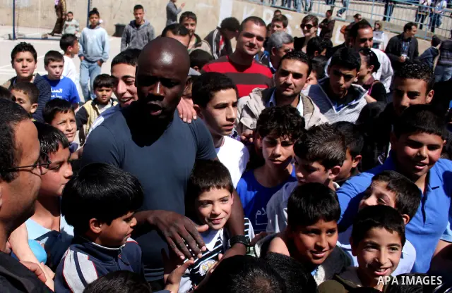 Former French soccer player Lilian Thuram visits a school in the West bank refugee camp of Kalandia, on 11 April 2011. Thuram is visiting the Palestinian territory in support of the education programme funded by France t...