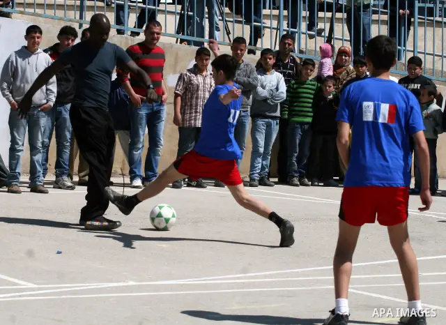 Former French soccer player Lilian Thuram visits a school in the West bank refugee camp of Kalandia, on 11 April 2011. Thuram is visiting the Palestinian territory in support of the education programme funded by France t...