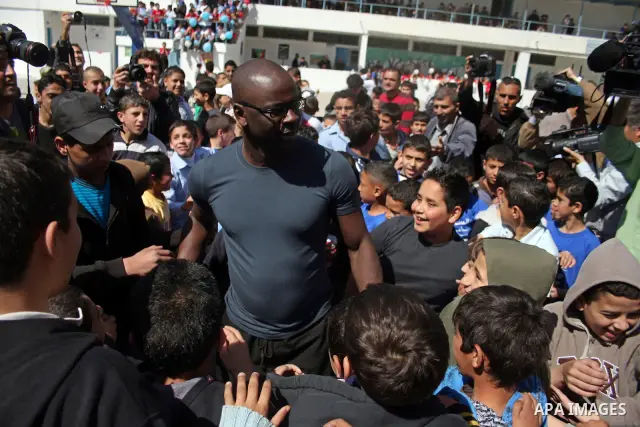 Former French soccer player Lilian Thuram visits a school in the West bank refugee camp of Kalandia, on 11 April 2011. Thuram is visiting the Palestinian territory in support of the education programme funded by France t...