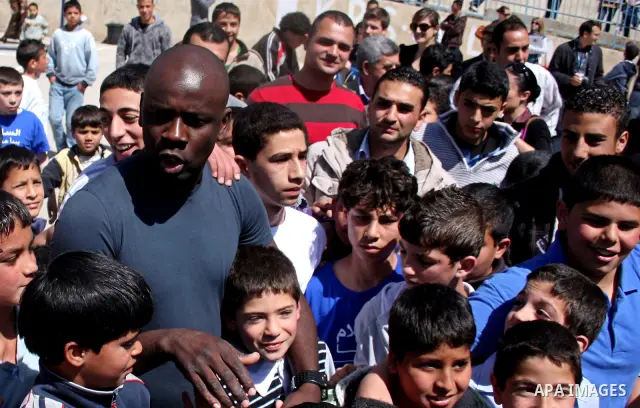 Former French soccer player Lilian Thuram visits a school in the West bank refugee camp of Kalandia, on 11 April 2011. Thuram is visiting the Palestinian territory in support of the education programme funded by France t...