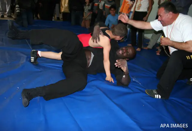 Former French football player Lilian Thuram plays with a Palestinian boy and a referee following a wrestling game at the Tareq Ben Ziad Club in the West Bank city of Hebron on April 13, 2011. Thuram is visiting the Pales...