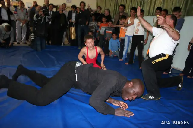 Former French football player Lilian Thuram plays with a Palestinian boy and a referee following a wrestling game at the Tareq Ben Ziad Club in the West Bank city of Hebron on April 13, 2011. Thuram is visiting the Pales...