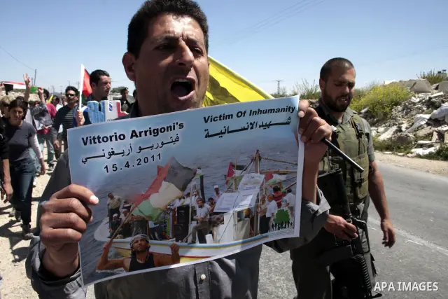 A protester holds a picture of the Italian flag and the birth date of Vittorio Arrigoni after kidnapping him in Gaza during a demonstration against Israel's controversial separation barrier in the West Bank village of Ma...