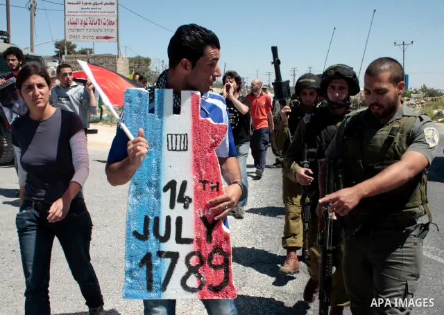 A protester holding a placard depicting the Italian flag and the birth date of Vittorio Arrigoni after kidnapping him in Gaza argue with Israeli soldiers during a demonstration against Israel's controversial separation b...