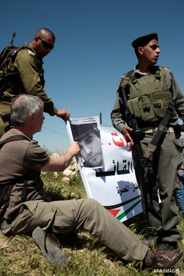 A protester holding a picture of the Italian flag and the birth date of Vittorio Arrigoni after kidnapping him in Gaza argue with Israeli soldiers during a demonstration against Israel's controversial separation barrier...