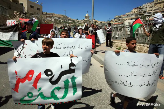 Palestinians hold national flag and placards during a protest in support with Gaza Strip and against the Israeli aggression on it, in the east Jerusalem neighborhood of Silwan on April 15, 2011. Photo by Sliman Khader