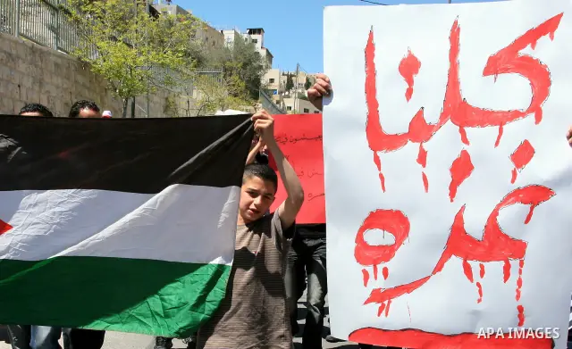 Palestinians hold national flag and placards during a protest in support with Gaza Strip and against the Israeli aggression on it, in the east Jerusalem neighborhood of Silwan on April 15, 2011. Photo by Sliman Khader