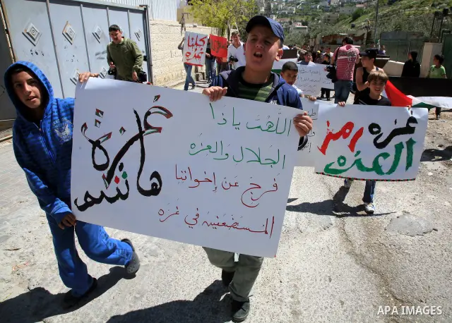 Palestinians hold national flag and placards during a protest in support with Gaza Strip and against the Israeli aggression on it, in the east Jerusalem neighborhood of Silwan on April 15, 2011. Photo by Sliman Khader