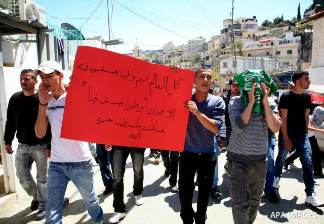 Palestinians hold national flag and placards during a protest in support with Gaza Strip and against the Israeli aggression on it, in the east Jerusalem neighborhood of Silwan on April 15, 2011. Photo by Sliman Khader
