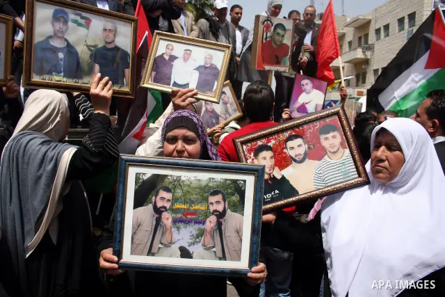 Palestinians hold pictures of their relatives who are imprisoned in an Israeli jail during a protest for the Prisoners Day which will be held on Sunday, in the West Bank city of Ramallah April 16, 2011. Photo by Issam Ri...