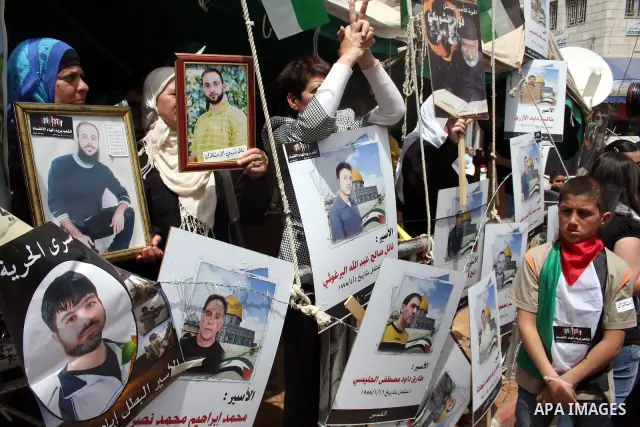 Palestinians hold pictures of their relatives who are imprisoned in an Israeli jail during a protest for the Prisoners Day which will be held on Sunday, in the West Bank city of Ramallah April 16, 2011. Photo by Issam Ri...