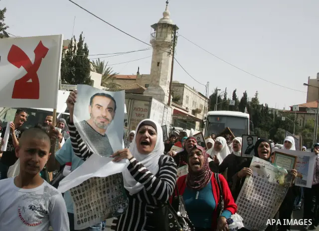 Palestinians hold pictures of prisoners jailed in Israel, including Fatah leader Marwan Barghouti, foreground left and right, during a protest for the upcoming Prisoner's Day, in the West Bank city of Jerusalem Saturday,...