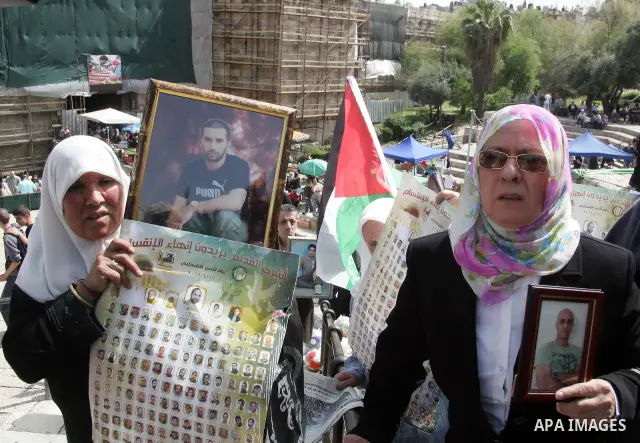 Palestinians hold pictures of prisoners jailed in Israel, including Fatah leader Marwan Barghouti, foreground left and right, during a protest for the upcoming Prisoner's Day, in the West Bank city of Jerusalem Saturday,...