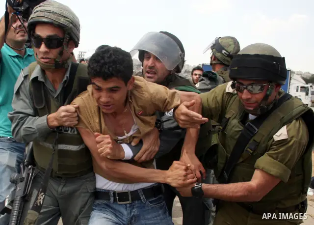 Israeli soldiers detain a Palestinian youth during a protest outside Ofer prison, near the West Bank city of Ramallah, April 17, 2011, calling for the release of Palestinian prisoners from Israeli jails. April 17 marks P...