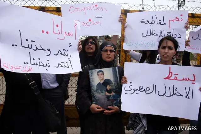 Palestinians hold pictures of their jailed relatives during a protest outside Ofer prison, near the West Bank city of Ramallah, April 17, 2011, calling for the release of Palestinian prisoners from Israeli jails. April 1...