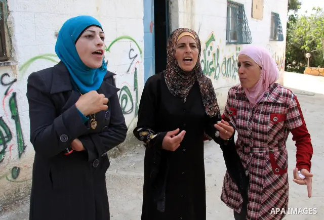 Palestinian Nouf Awad (C), mother of Hakim Awad, suspected in a stabbing attack that killed Jewish settler family, talks to journalists at her house in the West Bank village of Awarta near Nablus, Sunday, April 17, 2011....