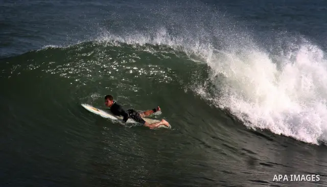 In this photo taken on April 14,2011, a Palestinian youth surf in the Mediterranean Sea off the coast of Gaza City, as a hot weather hits Gaza Strip. Photo by Mahmoud Nassar