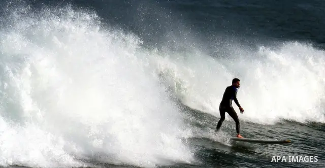 In this photo taken on April 14,2011, a Palestinian youth surf in the Mediterranean Sea off the coast of Gaza City, as a hot weather hits Gaza Strip. Photo by Mahmoud Nassar