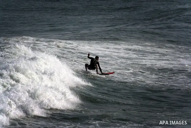 In this photo taken on April 14,2011, a Palestinian youth surf in the Mediterranean Sea off the coast of Gaza City, as a hot weather hits Gaza Strip. Photo by Mahmoud Nassar