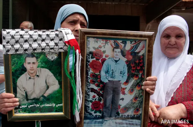 Palestinians hold up a photo of jailed family members as they take part in a rally, one of several taking place across the Israeli occupied West Bank and Gaza Strip, calling for the release of Palestinians being held in...