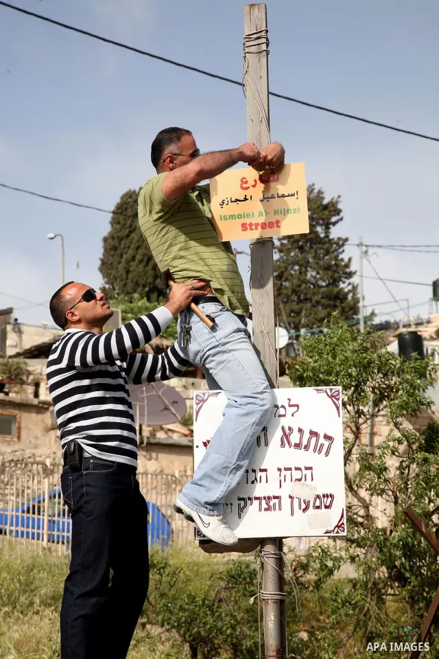 Palestinian youths lay a placard printed with Arabic name of a street during the project of Arabization of the streets in the neighborhood of Sheikh Jarrah in East Jerusalem on April 19,2011. Photo by Sliman Khader
